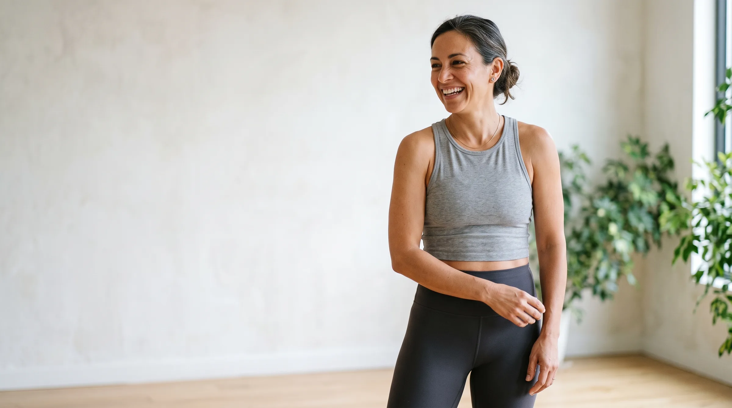 Woman in athletic wear smiling in a bright, sunlit room
